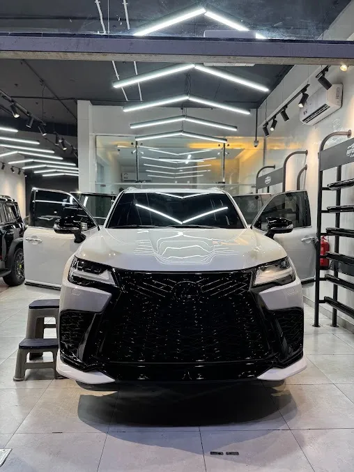 سيارة دفع رباعي بيضاء داخل صالة AUTOMOBILE CAR CENTER تحت إضاءة السقف