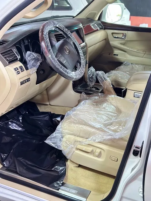 مقصورة سيارة بمقاعد فاتحة مغطاة بالنايلون أثناء التنظيف